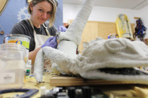 Woman sculpting a lizard.